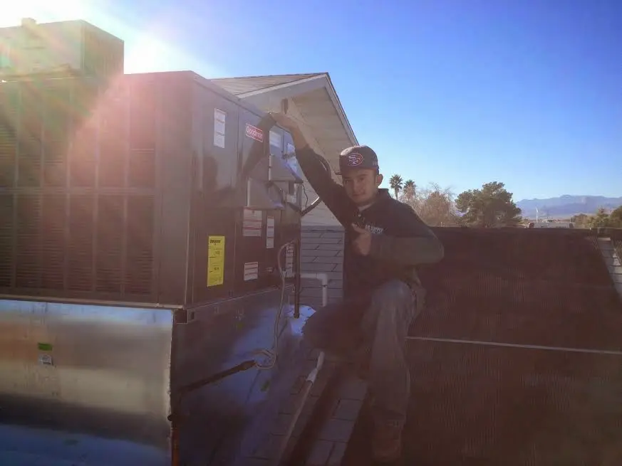 HVAC technician performing AC Tune-Up on a rooftop unit in Howland Center